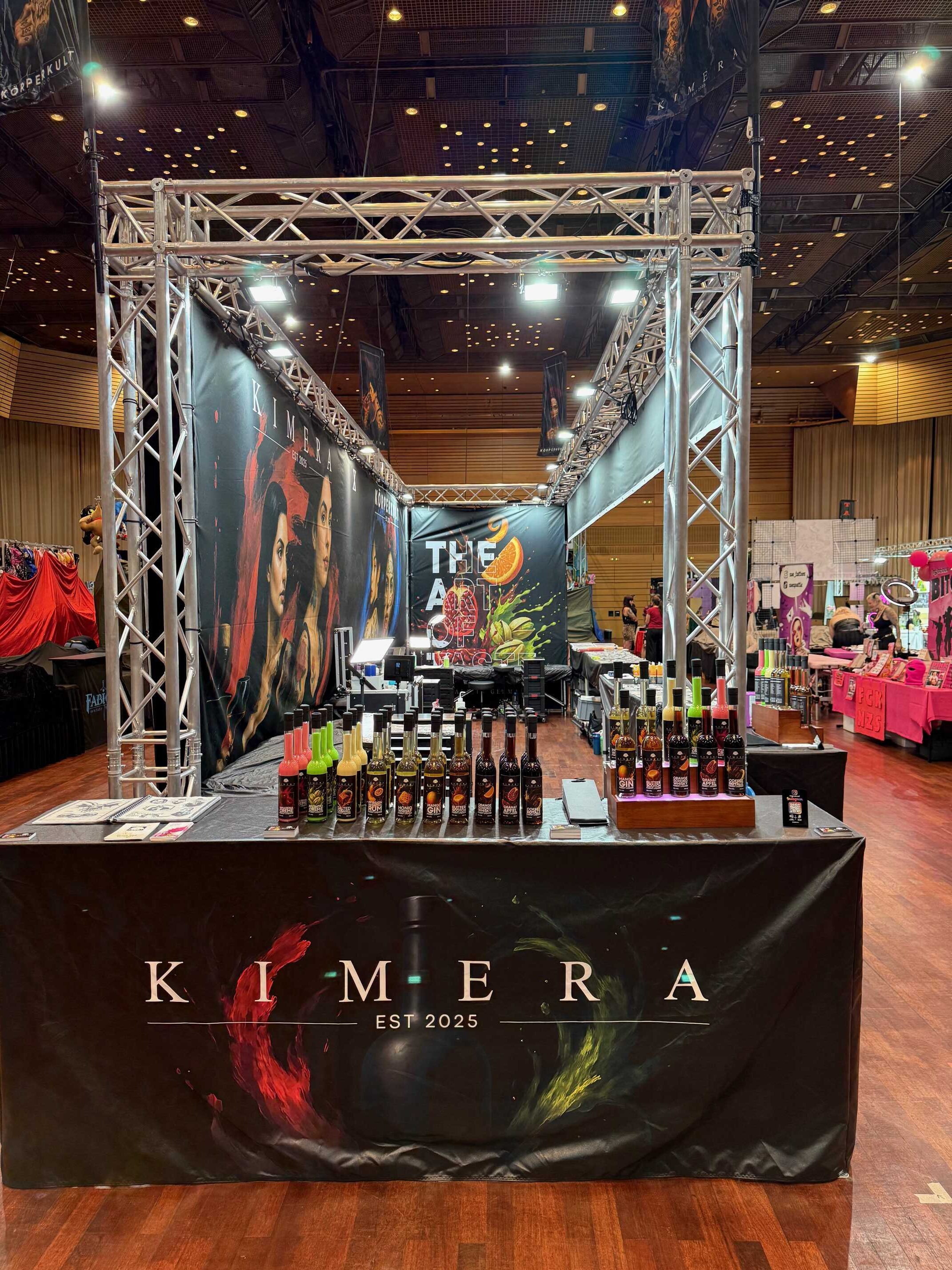 Messestand mit Spirituosenflaschen auf braunem Holzboden; bunte Etiketten.