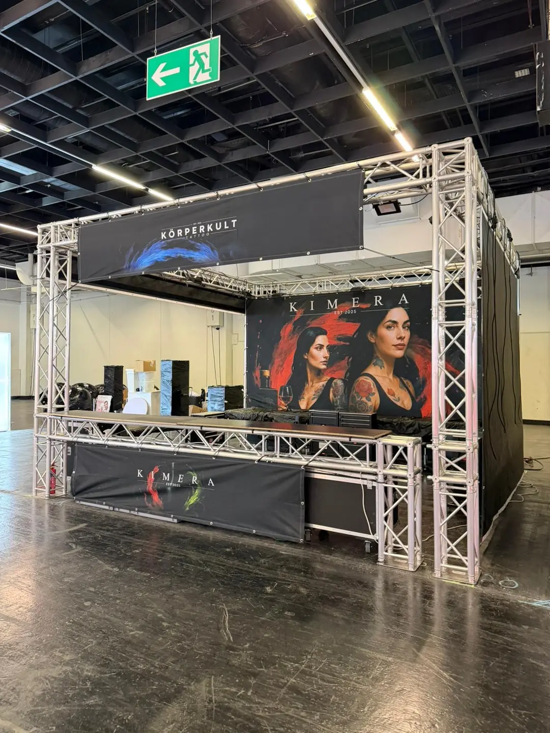 Messestand aus Traversen mit Kimera Plakat zweier taetowierter Frauen