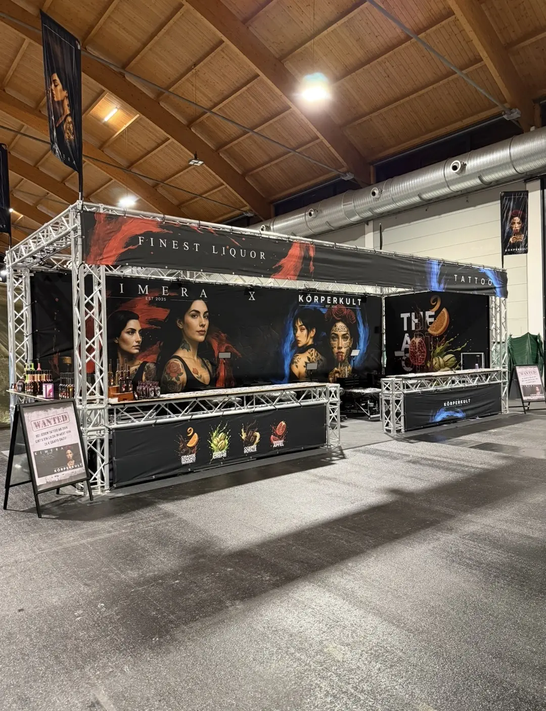 Messestand in Schwarz und Rot mit Likoerflaschen und tätowierten Frauenbildern