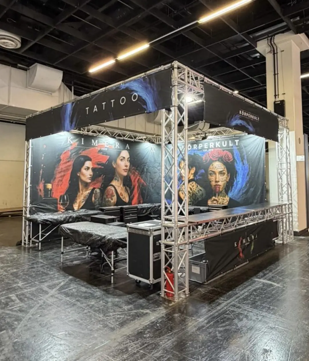 Tattoo Messestand mit grossen Portraits taetowierter Frauen in dunklen Farben