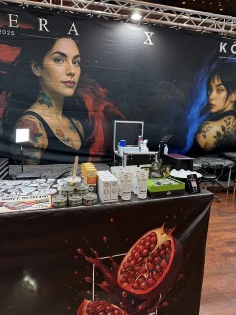 Messestand mit Tattoo Pflegeprodukten und grossen Bannern taetowierter Frauen